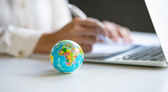 Photo of a globe with person working in the background