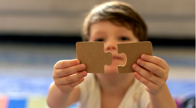 Image of little boy fitting two pieces of jigsaw