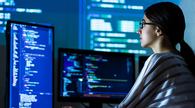 Software developer freelancer woman female in glasses work with program code C++ Java Javascript on wide displays at night Develops new web desktop mobile application or framework Projector background